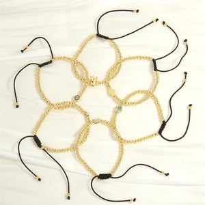 Detailed flat lay of golden bead bracelets with evil eye and Hamsa hand charms on white silk