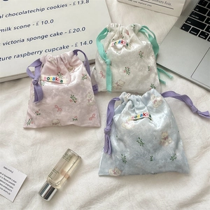 Detailed view of satin cartoon bear drawstring bags in pink, white, and blue colors