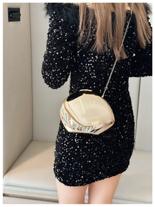 Macro detail of gold mirrored metal evening clutch with fine chain and sleek finish