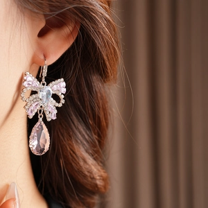 Macro shot of bow earrings with pink teardrop crystal and stones on a model