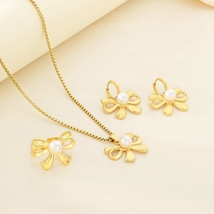 Detail shot of golden bow necklace and earrings set with elegant white pearls