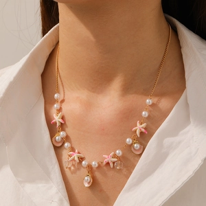 Detail of beaded necklace with gold chain, white pearls, pink starfish, and shell pendants