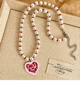 Detail of a vintage pearl heart necklace featuring pink pendant and elegant red beads