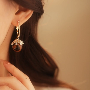 Detail of leopard print ball earring with gold diamond-encrusted hook on model