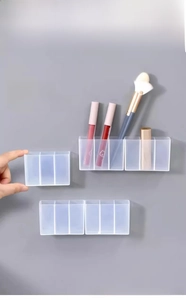 Close-up of wall-mounted clear storage box with multiple slots for makeup and stationery