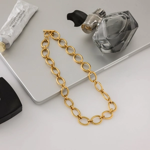 Mise à plat d'un collier géométrique en acier titane doré sur un ordinateur avec accessoires
