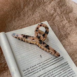 Macro view of tortoiseshell acetate hair claw with golden metal base on vintage book