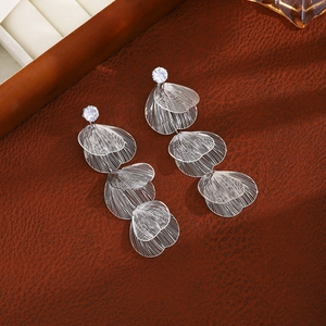 Detailed macro of silver-colored tassel earrings with intricate wire-mesh leaf design