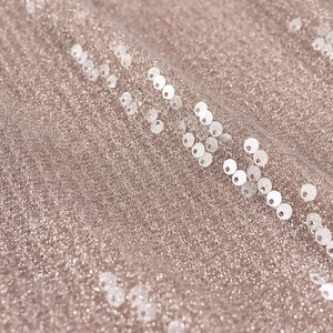 Macro shot of beige champagne knitted mesh fabric with white sequin texture details