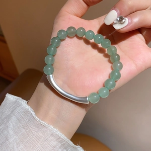 Close-up of green aventurine beaded bracelet with a matte silver metal tube on wrist