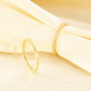 Nahaufnahme eines dünnen goldfarbenen, mattierten Edelstahlrings auf Seidenstoff