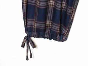 Detalle de puño de chaqueta a cuadros con cordón elástico en azul marino y rojo vivo