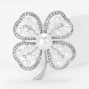 Macro detail of silver four-leaf clover brooch with white pearls and sparkling rhinestones