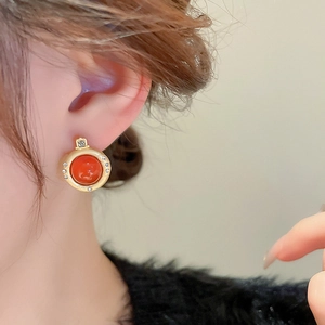 Gros plan de boucles d'oreilles vintage en or avec perles d'agate rouge sur l'oreille