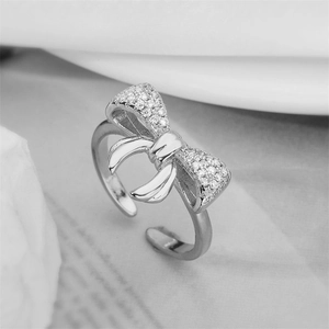 Macro dell'anello a fiocco argento con zirconi luccicanti su morbido tessuto bianco