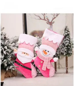 Detailed view of pink and white knitted Christmas stockings with plush Santa and Snowman