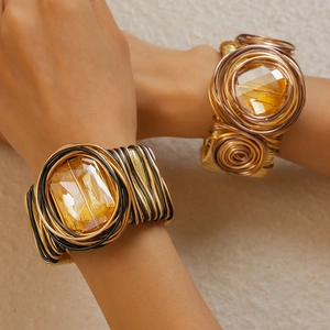 Detailed close-up of woven metallic gold and black bangles with large amber glass stones