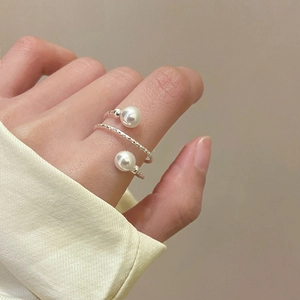 Detail of minimalist multilayer pearl open ring on hand with elegant silver finish