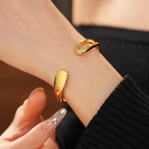 Detail of a gold-plated teardrop open bangle showing its minimalist asymmetric design