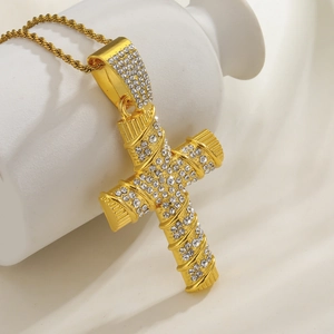 Close-up of gold cross pendant with cubic zirconia on a Cuban link chain necklace