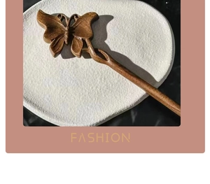 Close-up of a carved wooden butterfly hair pin with natural sandalwood grain on white plate