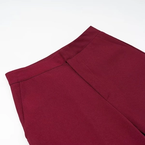 Detailed view of dark red high-waist trousers featuring structured waistband and side pockets