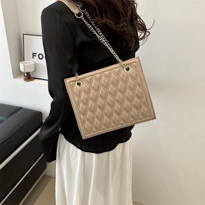 Quilted crossbody bag with gold chain strap worn by a model in a minimalist setting