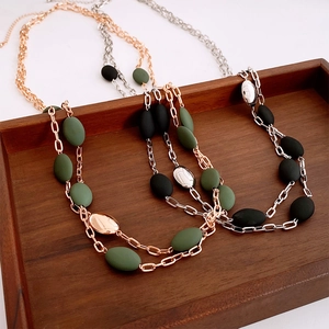 Detail of vintage layered chain necklace with matte oval beads on wooden tray