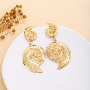 Close-up of golden shell-shaped vintage metal earrings with textured spiral design
