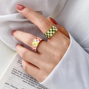 Close-up of checkered enamel rings on model hand with a vintage lifestyle aesthetic