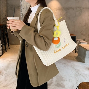 Detail of white quilted canvas tote with floral embroidery and Good Luck charm