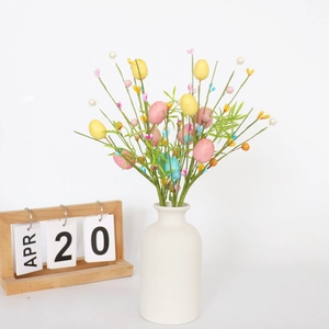 Dettaglio di rami con uova di Pasqua colorate e foglie verdi in un vaso bianco