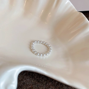 Close-up of a beaded pearl elastic ring placed on a white ceramic shell tray
