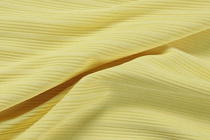 Vue macro de la texture du tissu en maille côtelée crème sur une robe ajustée