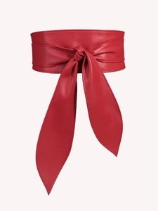 Detail of red faux leather waist belt showing soft texture and long elegant bow tie straps