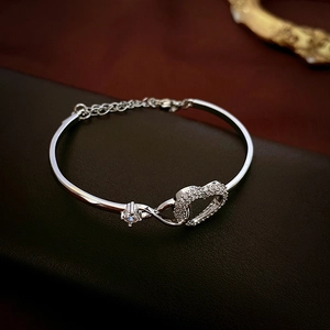 Macro view of silver heart and infinity link bracelet with pavé cubic zirconia detail