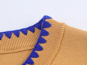 Macro detail of camel knit collar with striking blue triangular contrast embroidery