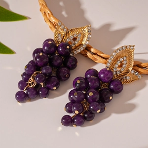 Détail de boucles d'oreilles raisin violet avec feuilles dorées serties de strass