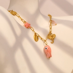 Detail of gold paperclip necklace with pink starfish and enamel flower charms on a bust