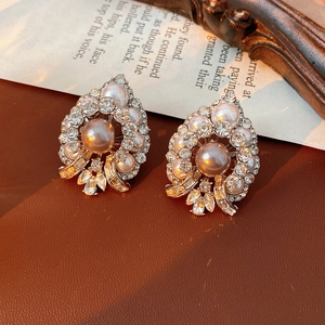 Macro shot of vintage pearl and rhinestone heart earrings with leaf detailing