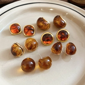 Macro shot of amber resin geometric earrings set in a ceramic dish with vintage textures