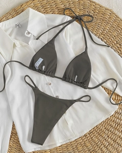 Detailed flat lay of dark olive green ribbed halter bikini set on woven mat
