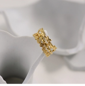 Macro shot of three stacked 18K gold-plated honeycomb and branch texture rings on ceramic