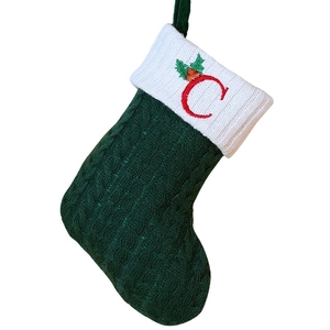 Green knitted Christmas stocking with white cuff and red embroidered letter C