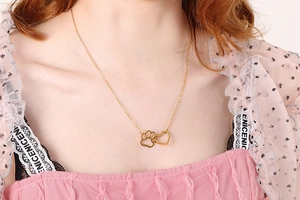 Close-up of gold titanium steel necklace featuring a heart and paw print pendant