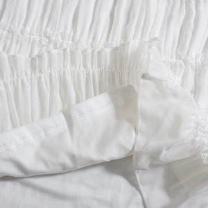 Detailed close-up of white pleated fabric showing fine stitching and tiered texture