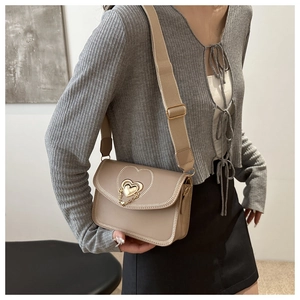 Close-up of a khaki crossbody bag featuring heart-shaped metal lock and wide canvas strap
