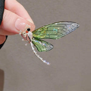 Macro shot of dragonfly brooch with translucent green wings and gold metal detailing