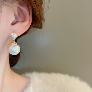 Close-up of elegant pearl drop earrings with sparkling zircon on a model wearing them