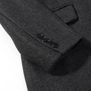 Macro shot of dark grey wool coat sleeve featuring four elegant black buttons on the cuff
